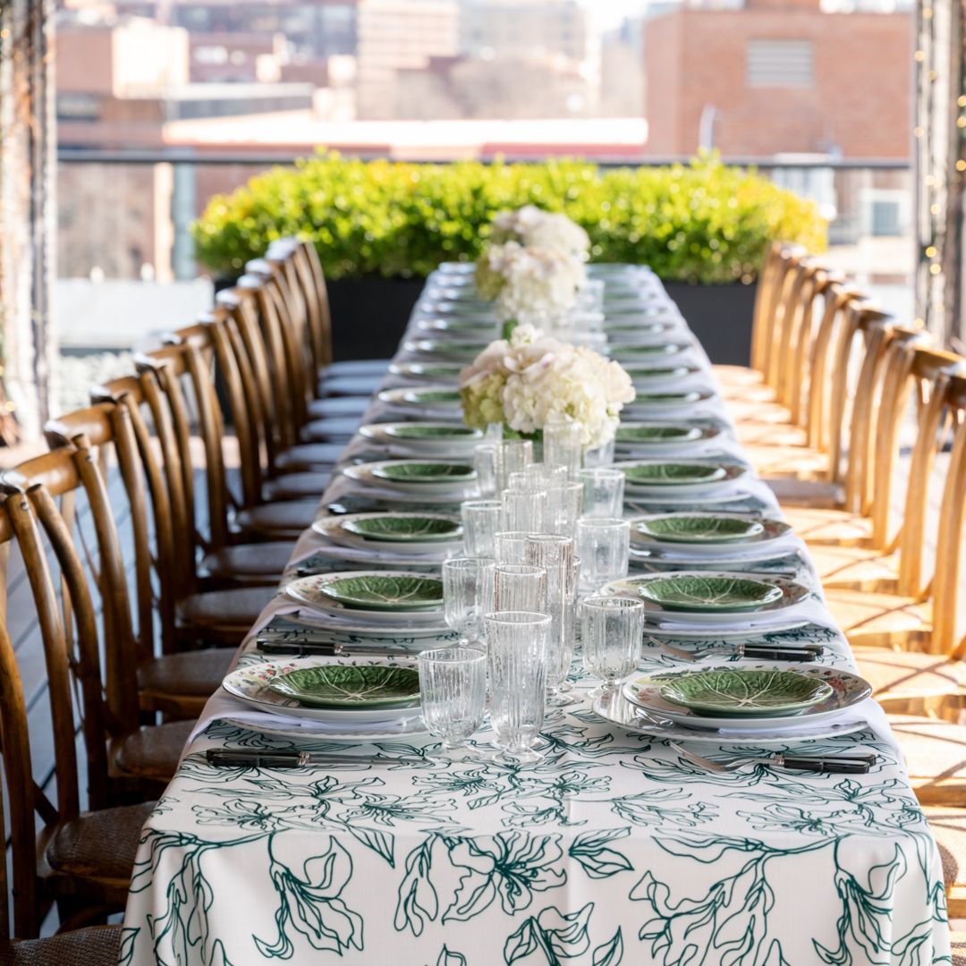 A long dining table set on a rooftop surrounded by wooden chairs.